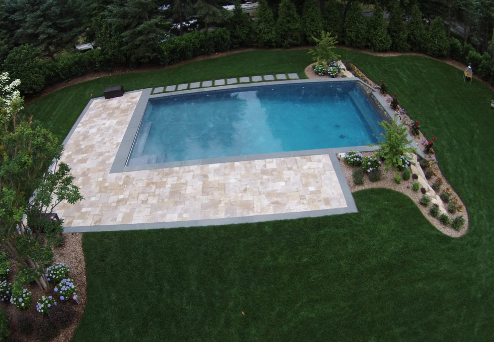 На фото: большой прямоугольный бассейн-инфинити на заднем дворе в стиле неоклассика (современная классика) с фонтаном и покрытием из каменной брусчатки
