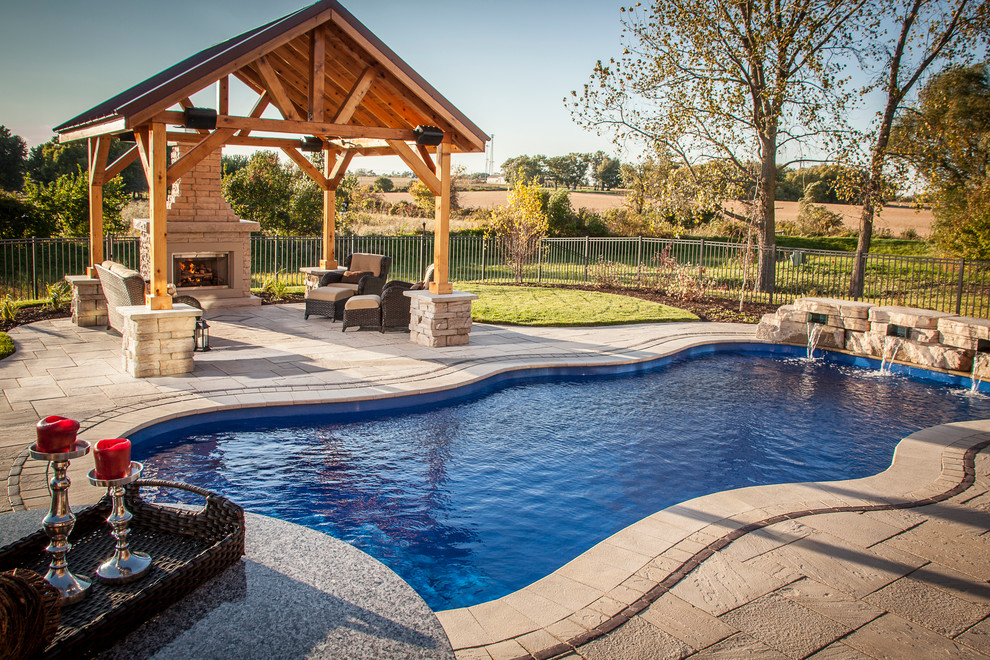 Ejemplo de piscina con fuente natural moderna de tamaño medio a medida en patio trasero con adoquines de piedra natural