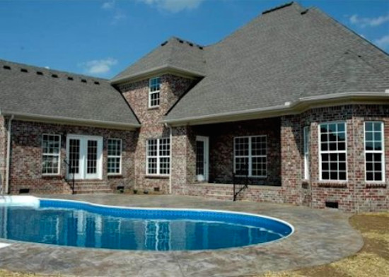 Example of a classic backyard stamped concrete and custom-shaped pool design in Nashville