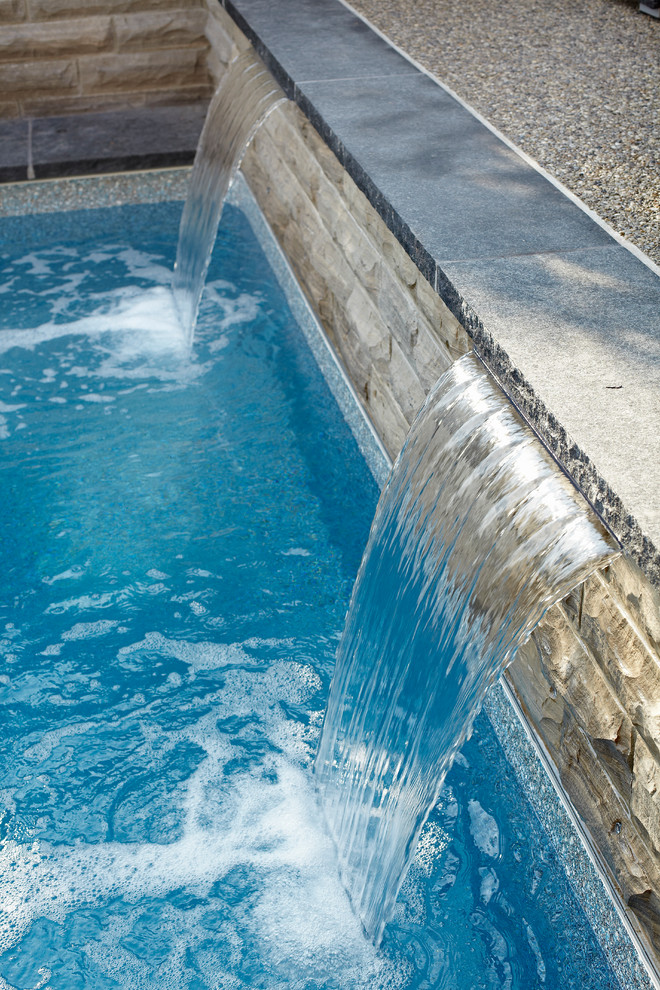 Immagine di una piccola piscina naturale moderna personalizzata dietro casa con fontane e pavimentazioni in pietra naturale