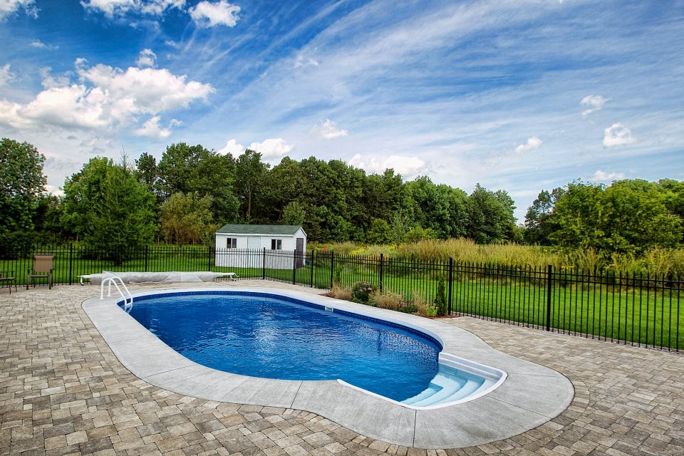 Imagen de piscina rústica de tamaño medio redondeada en patio trasero con adoquines de hormigón