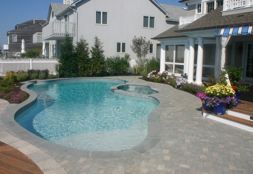 Esempio di una grande piscina costiera personalizzata dietro casa con pavimentazioni in mattoni