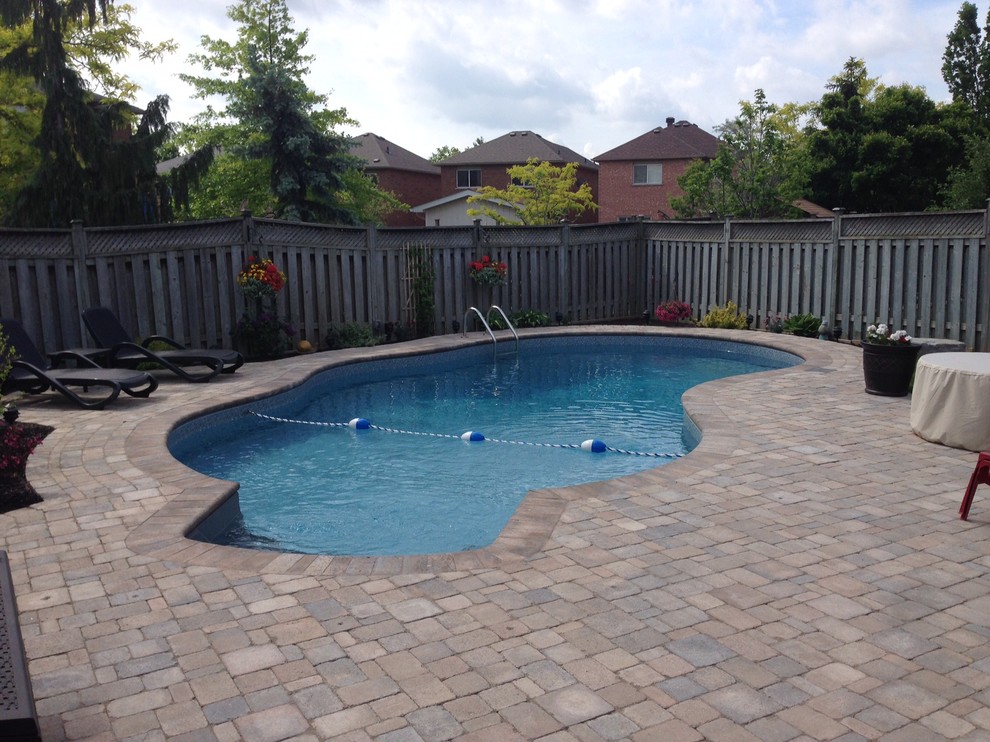 Ejemplo de piscina con fuente natural contemporánea grande tipo riñón en patio trasero con adoquines de hormigón