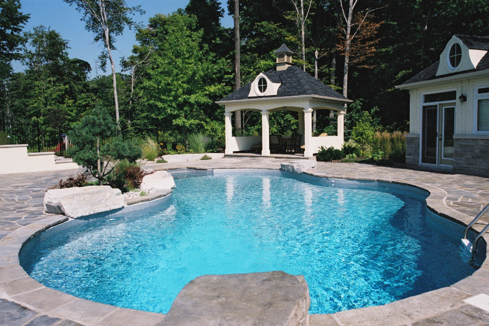 Idéer för en stor klassisk pool på baksidan av huset, med naturstensplattor och poolhus