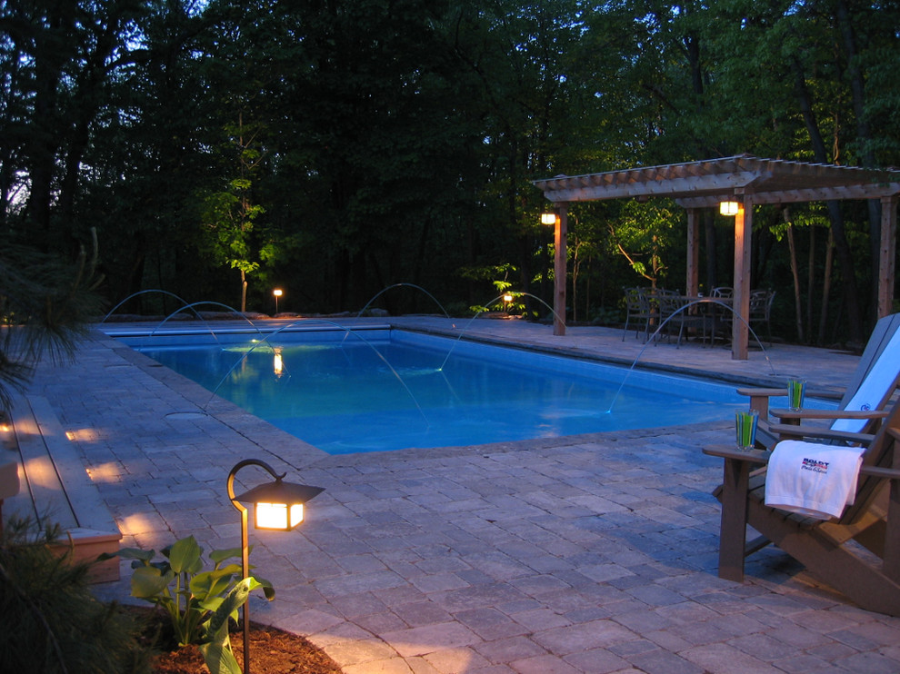 Imagen de piscina con fuente natural actual grande rectangular en patio trasero con adoquines de ladrillo