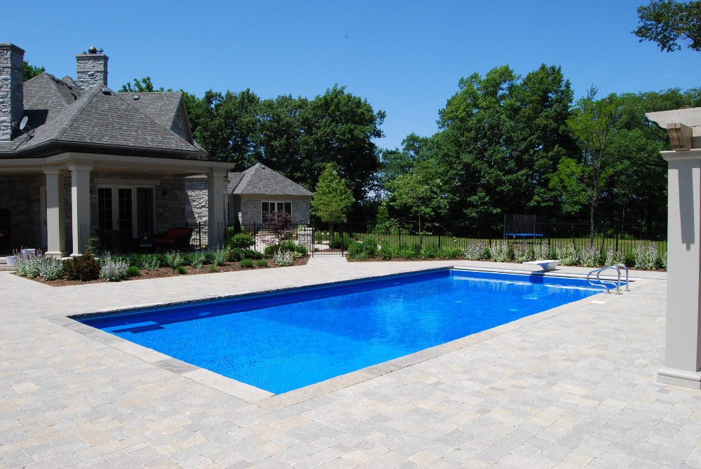 Modelo de casa de la piscina y piscina natural contemporánea grande rectangular en patio trasero con adoquines de ladrillo