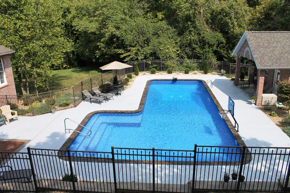 Imagen de piscina de estilo americano grande en forma de L en patio trasero con losas de hormigón