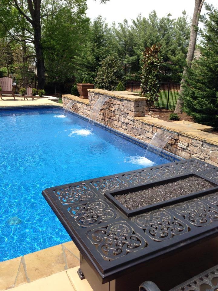 Foto de piscina con fuente natural de estilo americano de tamaño medio rectangular en patio trasero con adoquines de hormigón