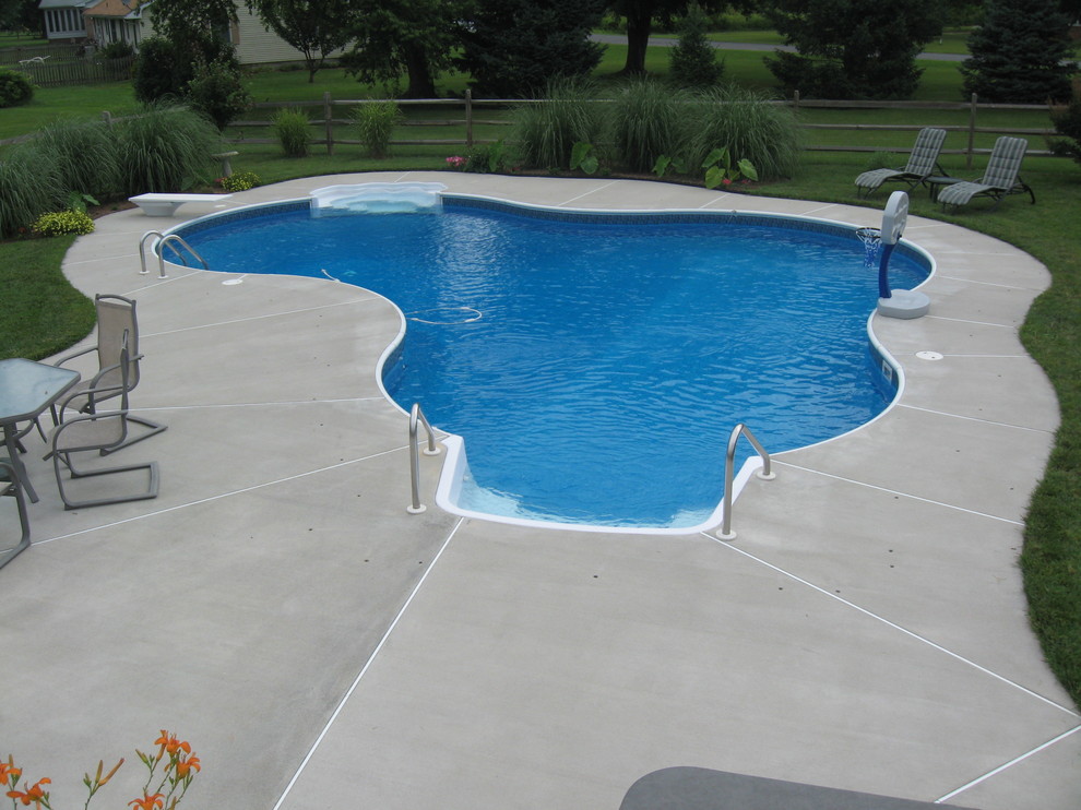На фото: спортивный бассейн произвольной формы, среднего размера на заднем дворе в классическом стиле с покрытием из бетонных плит с