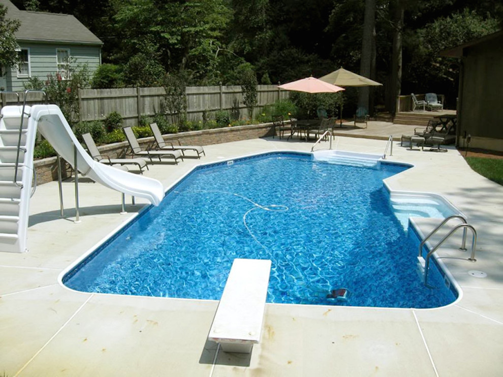 Ejemplo de piscina con tobogán alargada minimalista de tamaño medio rectangular en patio trasero con losas de hormigón