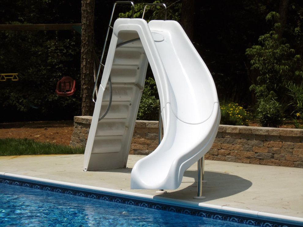 Ejemplo de piscina con tobogán alargada moderna de tamaño medio en forma de L en patio trasero con losas de hormigón