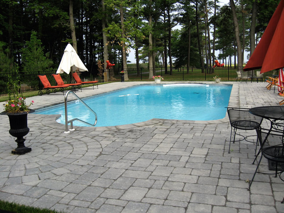 Imagen de piscina alargada minimalista grande rectangular en patio trasero con adoquines de hormigón
