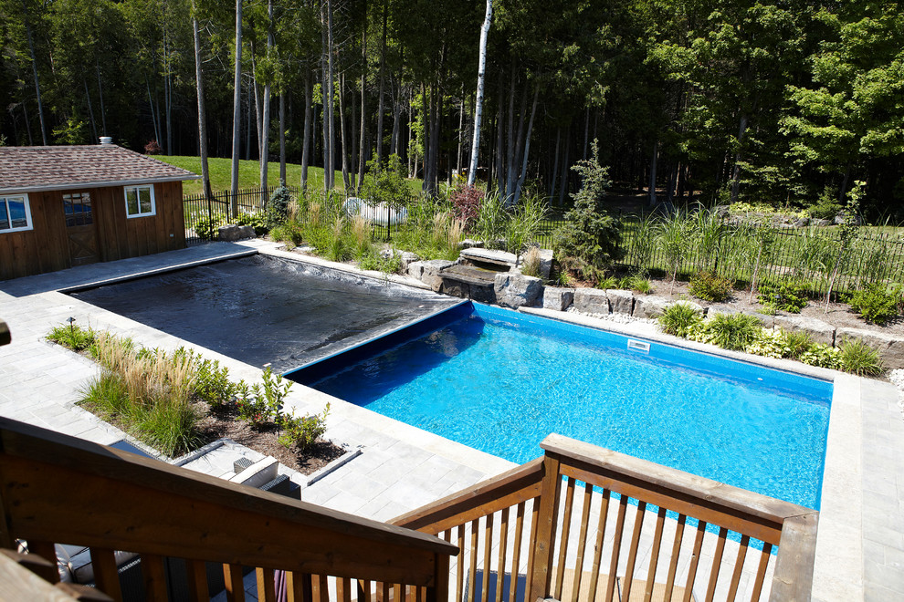 Diseño de piscina con fuente alargada actual grande rectangular en patio trasero con adoquines de ladrillo
