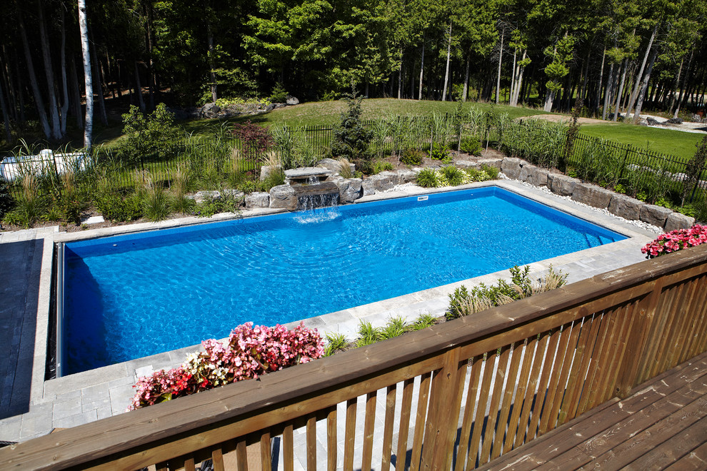 Foto de piscina con fuente alargada contemporánea grande rectangular en patio trasero con adoquines de ladrillo
