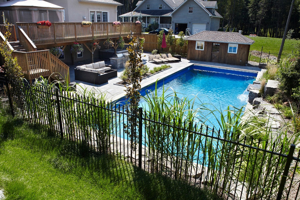 Large contemporary back rectangular lengths swimming pool in Toronto with a water feature and brick paving.
