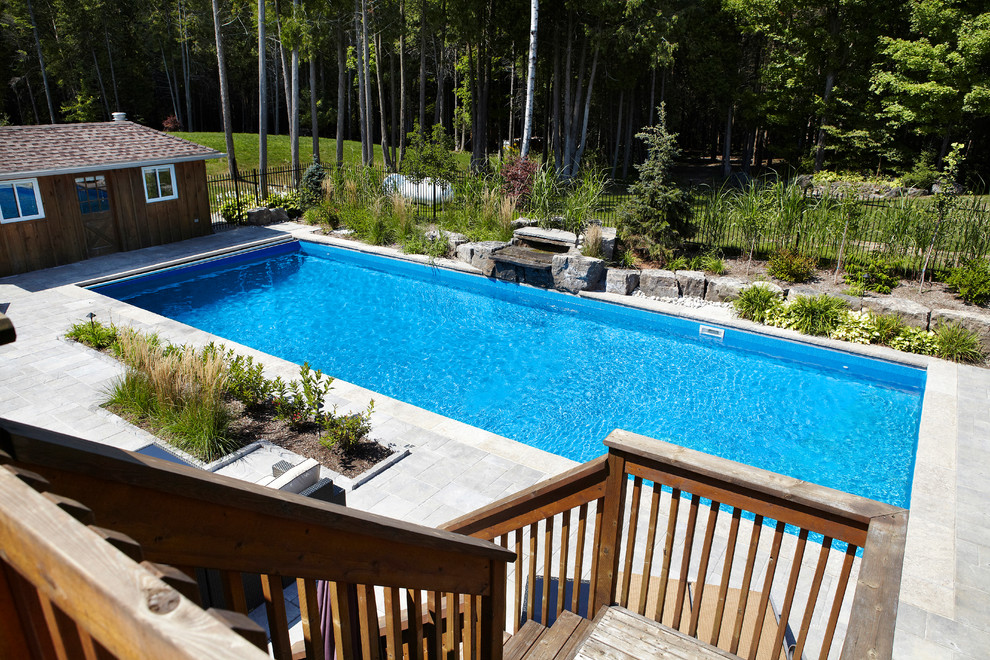 Imagen de piscina con fuente alargada contemporánea grande rectangular en patio trasero con adoquines de ladrillo