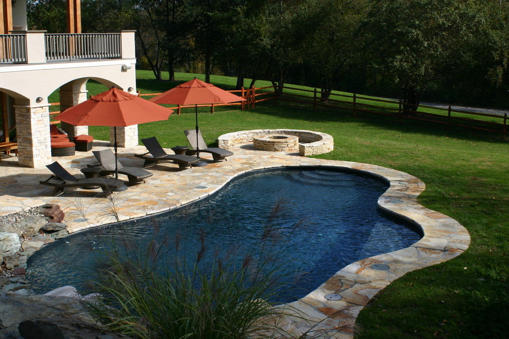 Пример оригинального дизайна: большой естественный бассейн произвольной формы на заднем дворе в стиле модернизм с водной горкой и покрытием из каменной брусчатки
