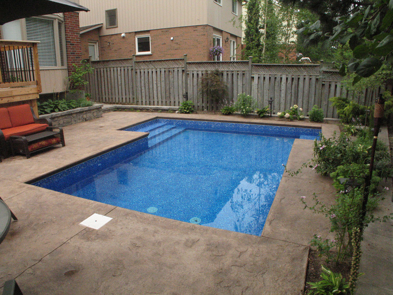 Immagine di una piccola piscina chic rettangolare dietro casa con cemento stampato