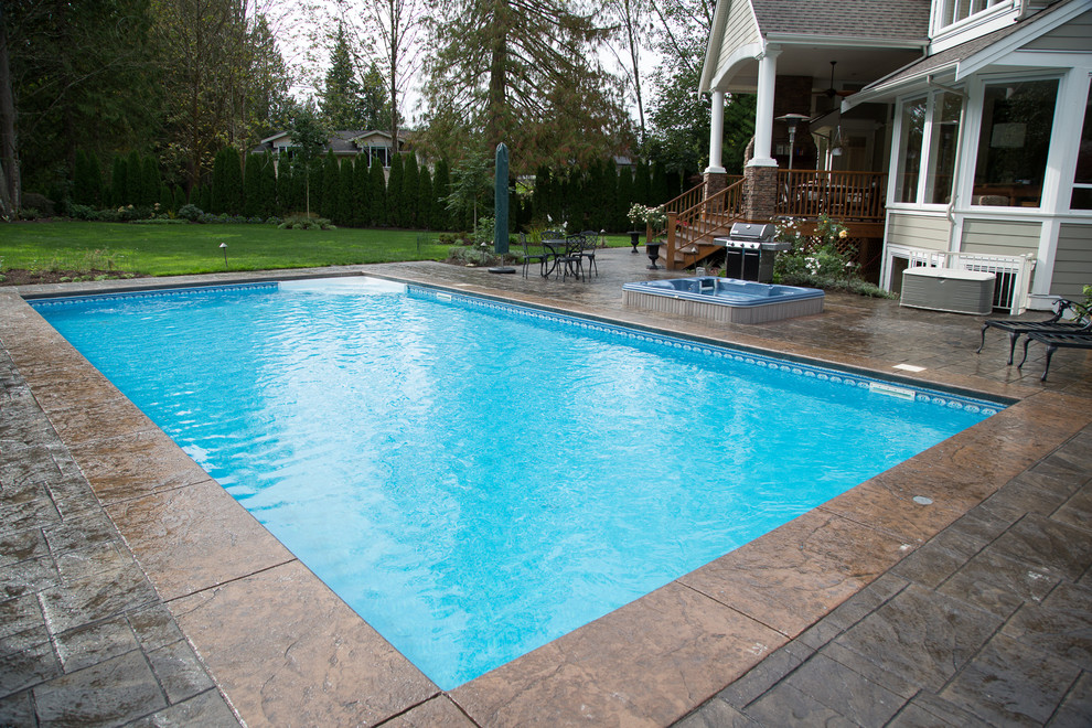 Esempio di una grande piscina monocorsia chic rettangolare dietro casa con una vasca idromassaggio e cemento stampato