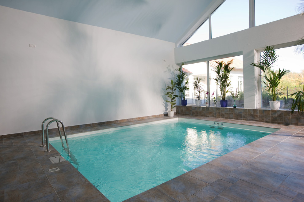Ispirazione per una grande piscina coperta fuori terra minimal personalizzata con una dépendance a bordo piscina e lastre di cemento