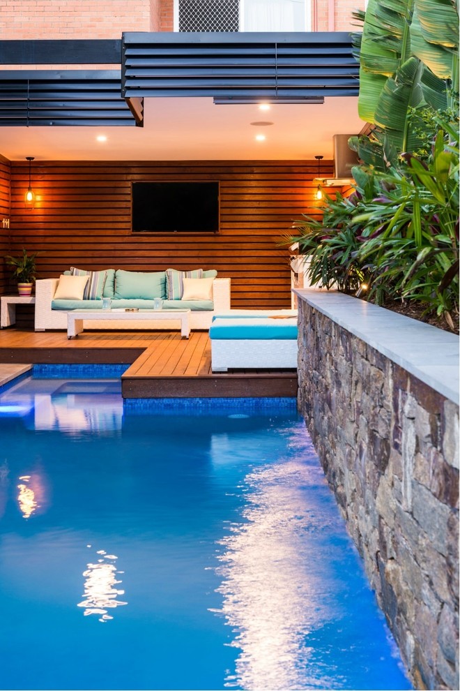 Ispirazione per una piscina monocorsia tropicale rettangolare di medie dimensioni e dietro casa con pedane