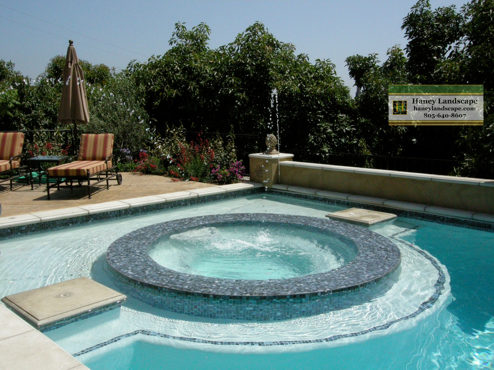 Idee per una grande piscina chic personalizzata dietro casa con pavimentazioni in pietra naturale e una vasca idromassaggio