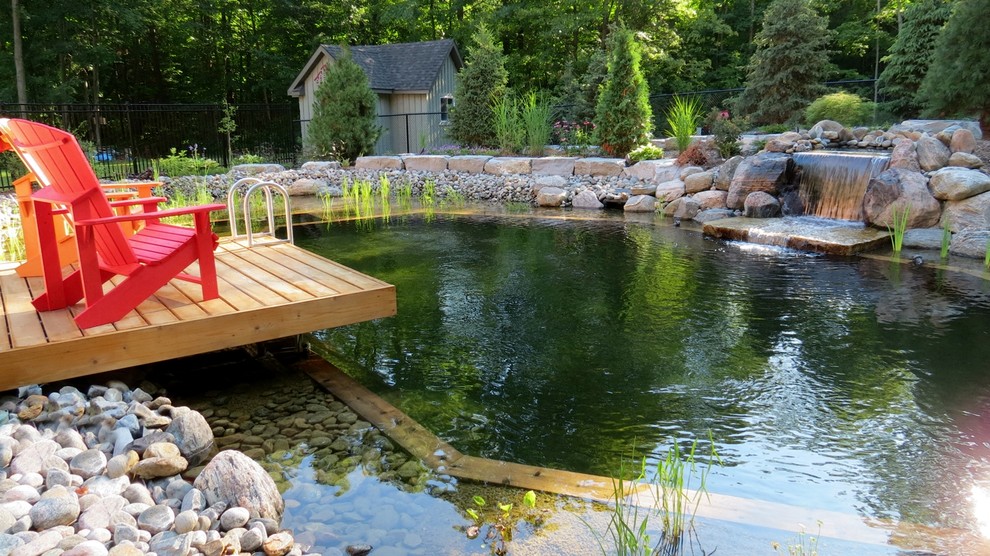 Esempio di una grande piscina naturale design personalizzata dietro casa con fontane e pavimentazioni in pietra naturale