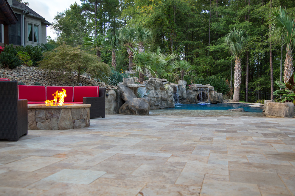 Foto de piscina con tobogán actual grande a medida en patio trasero con adoquines de piedra natural