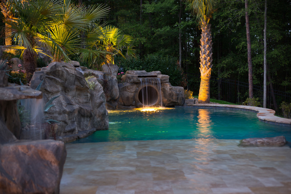 Ispirazione per un'ampia piscina tropicale personalizzata dietro casa con fontane e pavimentazioni in pietra naturale