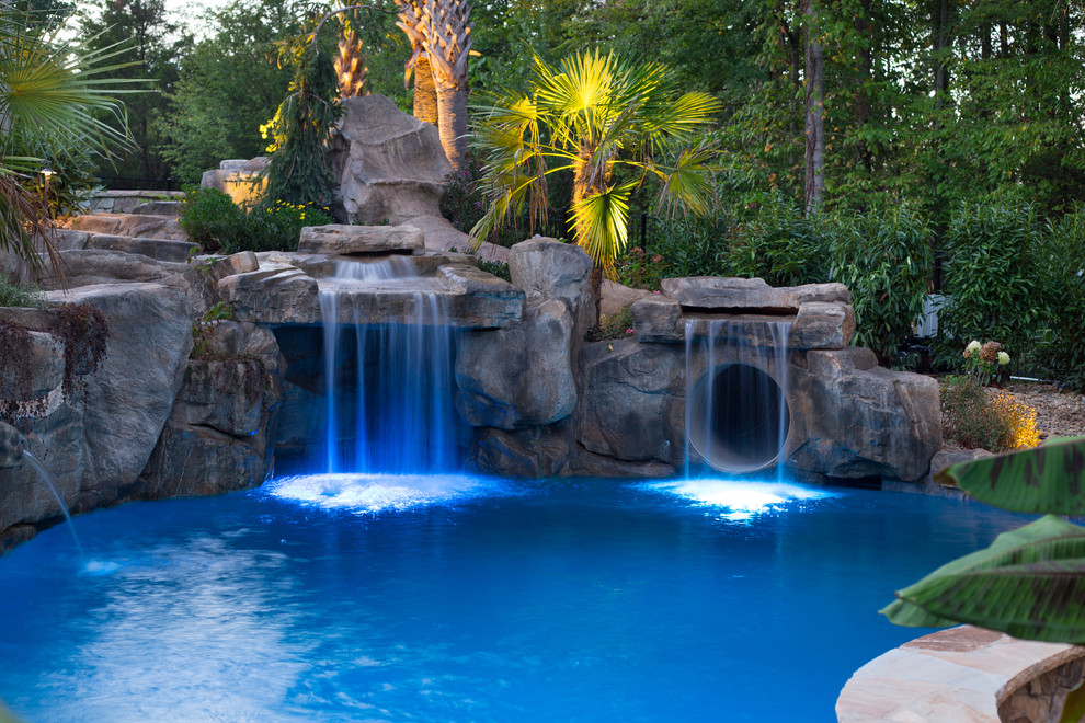 Foto de piscina con fuente exótica grande a medida en patio trasero con adoquines de piedra natural