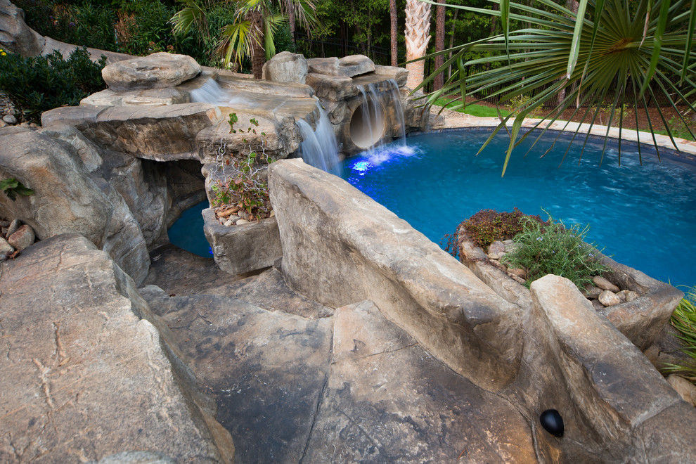 Ejemplo de piscina con fuente tropical extra grande a medida en patio trasero con adoquines de piedra natural