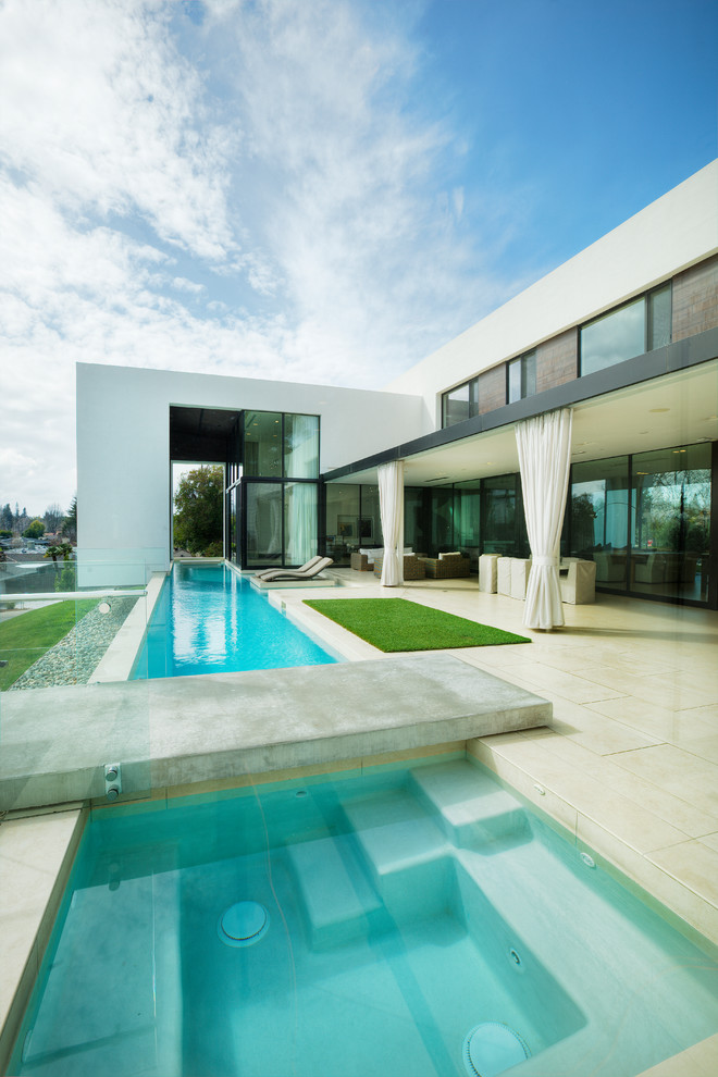 Immagine di una piscina monocorsia minimalista rettangolare di medie dimensioni e dietro casa con piastrelle e una vasca idromassaggio