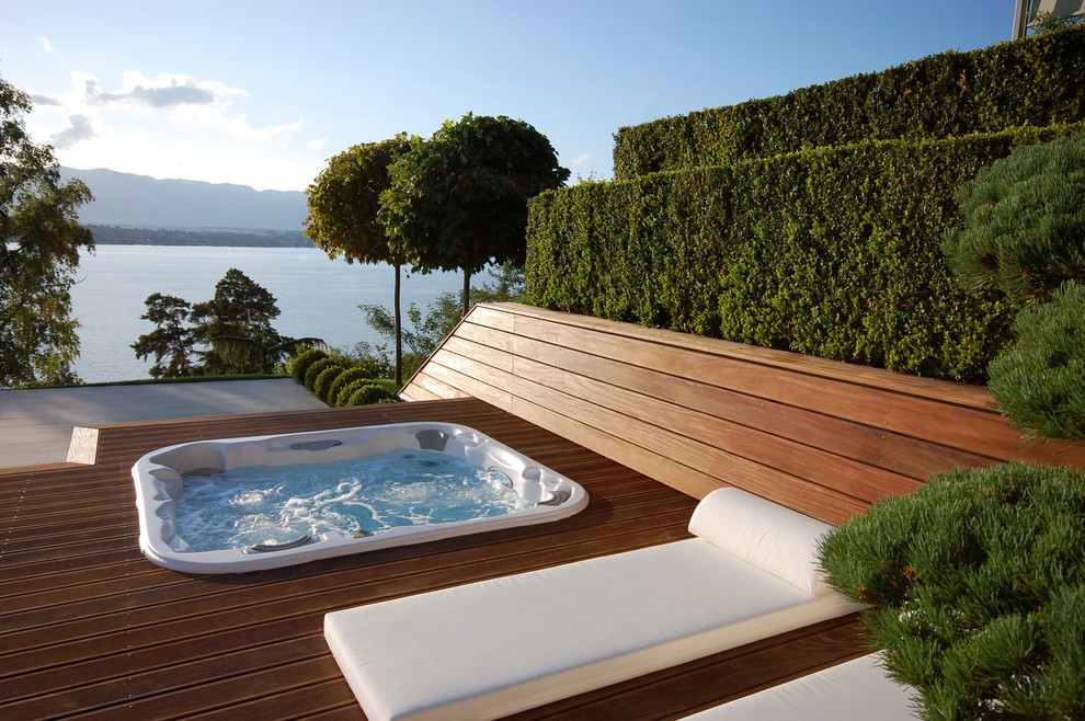 Aménagement d'une piscine hors-sol et arrière contemporaine de taille moyenne et rectangle avec un bain bouillonnant et une terrasse en bois.