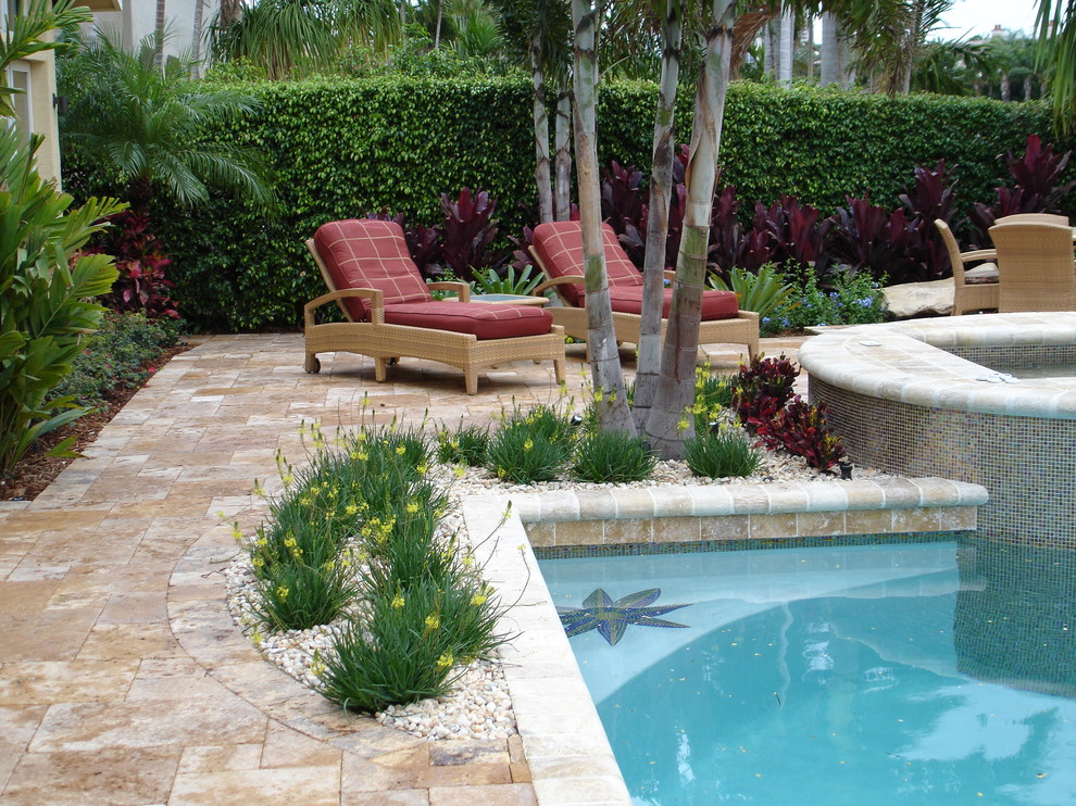 Esempio di una piscina a sfioro infinito tropicale rettangolare dietro casa e di medie dimensioni con pavimentazioni in pietra naturale e una vasca idromassaggio