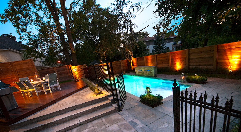 Imagen de piscina con fuente minimalista de tamaño medio rectangular en patio trasero con adoquines de hormigón