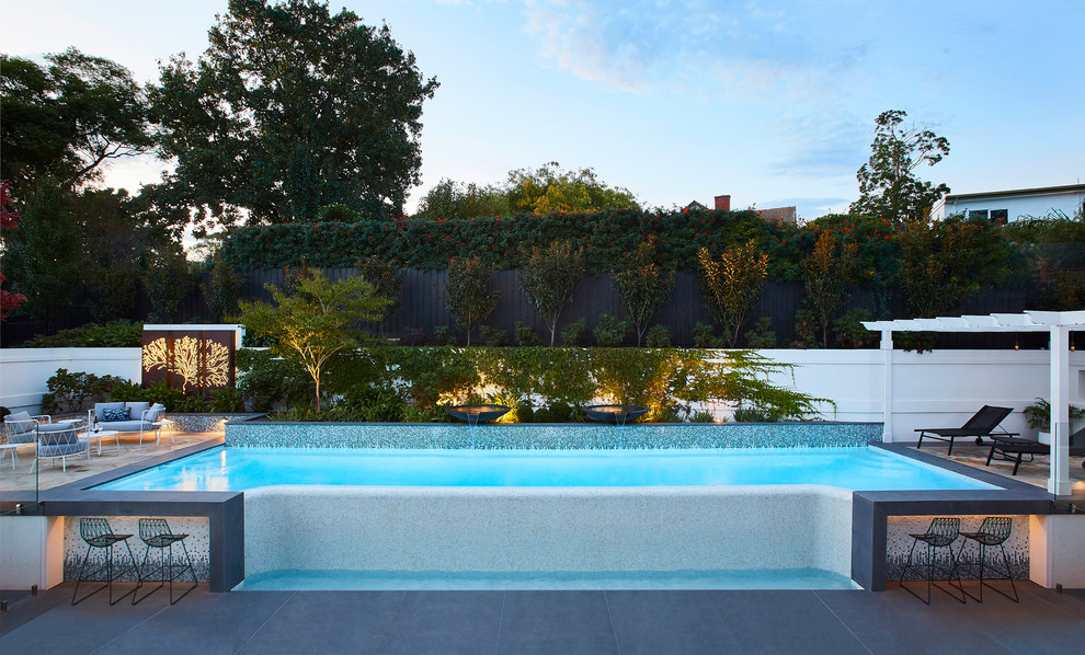 Esempio di una piscina fuori terra design personalizzata dietro casa con fontane e pavimentazioni in cemento