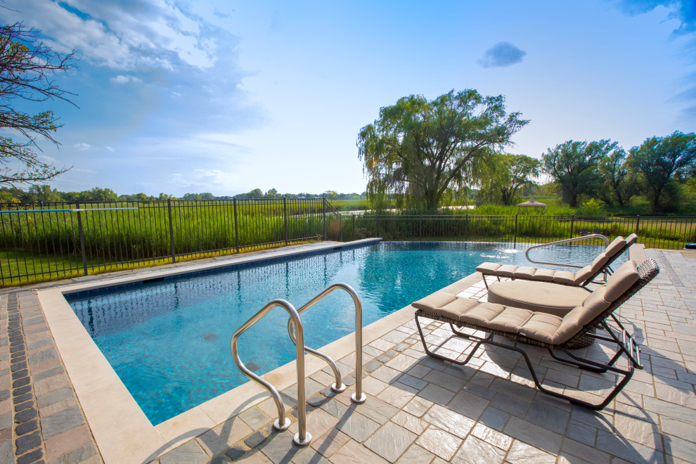 Esempio di una piscina a sfioro infinito classica personalizzata di medie dimensioni e dietro casa con paesaggistica bordo piscina e pavimentazioni in cemento