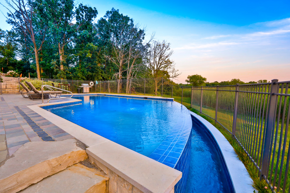 Foto de piscina infinita clásica de tamaño medio a medida en patio trasero con paisajismo de piscina y adoquines de hormigón