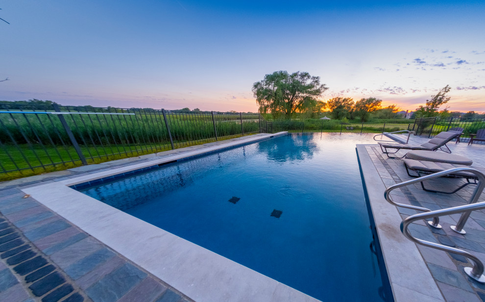 Ispirazione per una piscina a sfioro infinito tradizionale personalizzata di medie dimensioni e dietro casa con paesaggistica bordo piscina e pavimentazioni in cemento