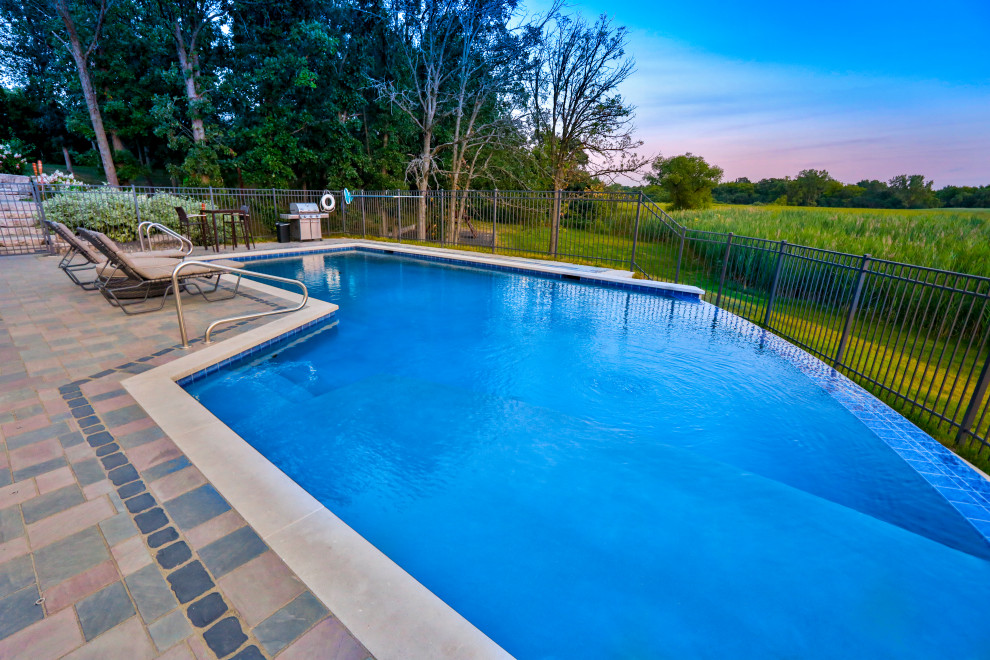 Foto di una piscina a sfioro infinito chic personalizzata di medie dimensioni e dietro casa con paesaggistica bordo piscina e pavimentazioni in cemento