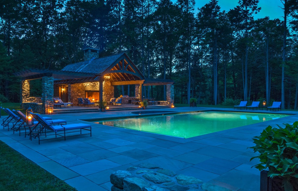 Large rustic back rectangular natural swimming pool in Boston with a pool house and concrete paving.