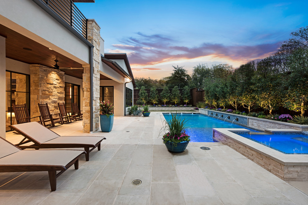 Ejemplo de piscina con fuente alargada actual de tamaño medio rectangular en patio trasero con suelo de baldosas