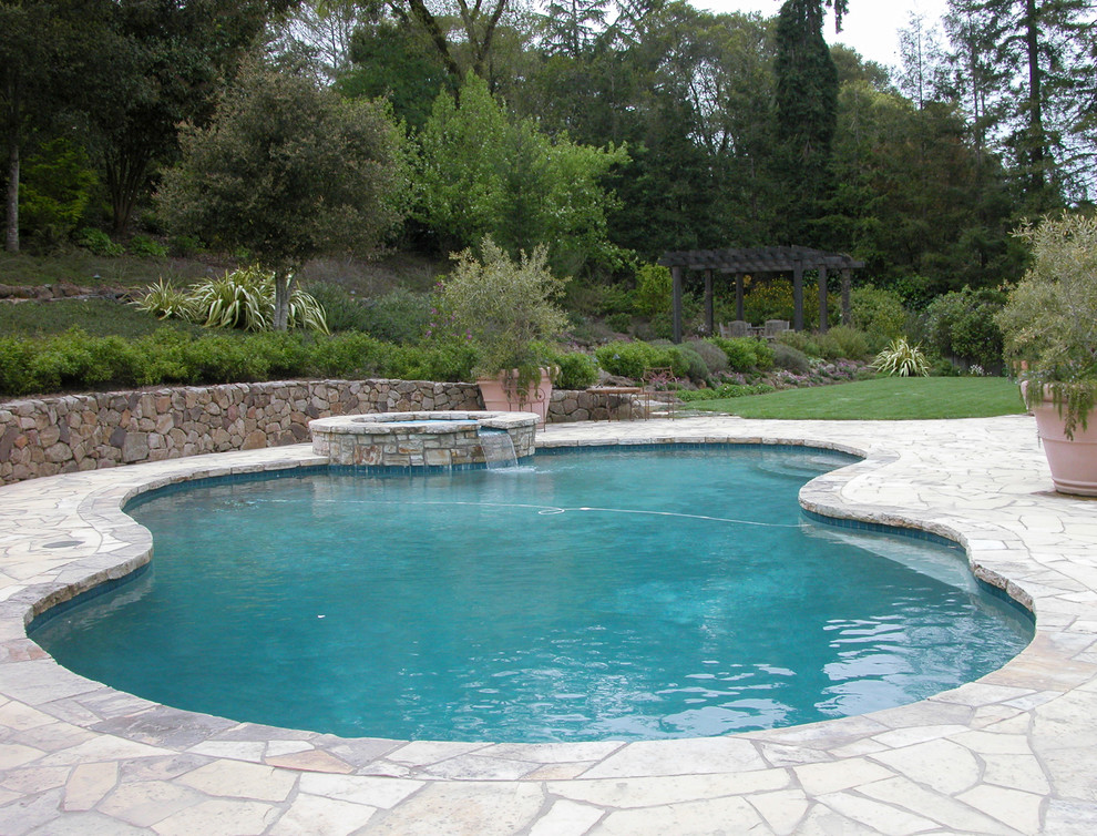 На фото: большой бассейн произвольной формы на заднем дворе в классическом стиле с покрытием из каменной брусчатки с
