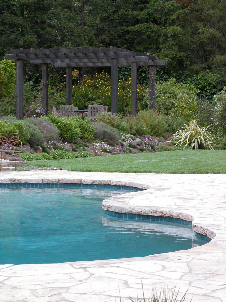 Imagen de piscina tradicional grande a medida en patio trasero con paisajismo de piscina y adoquines de piedra natural