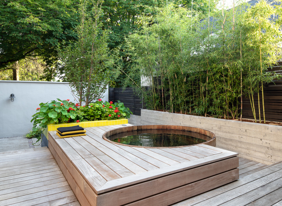 Cette image montre une petite piscine design ronde avec un bain bouillonnant et une terrasse en bois.