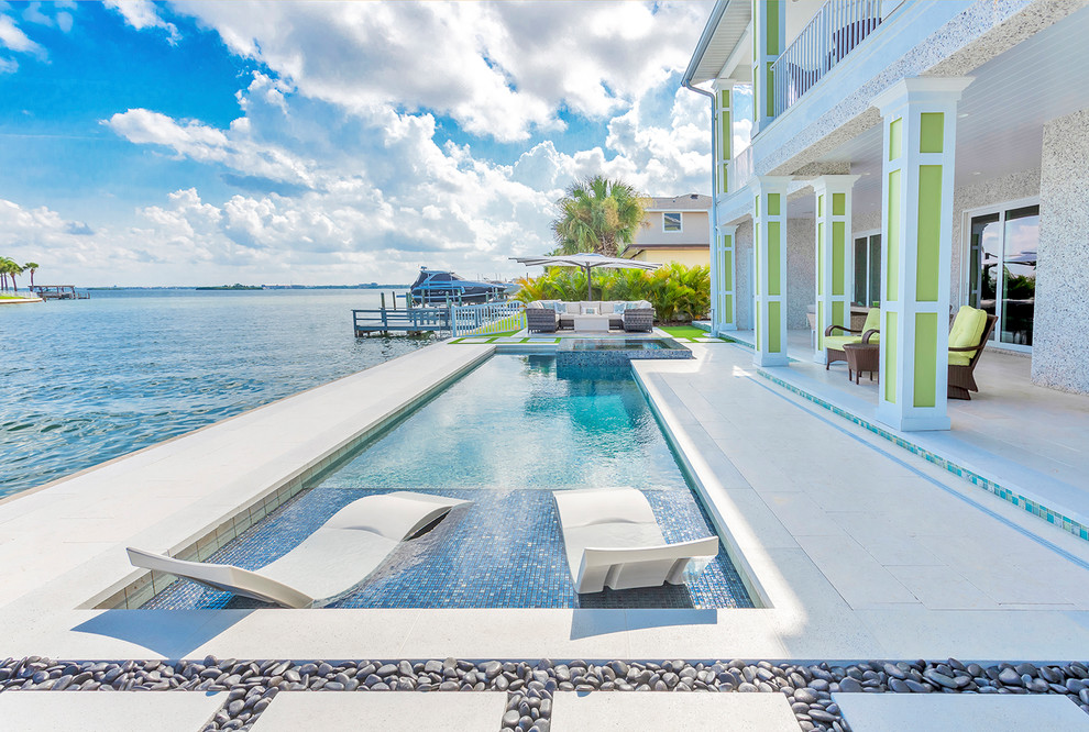 This is an example of a beach style courtyard rectangular hot tub in Tampa with tiled flooring.