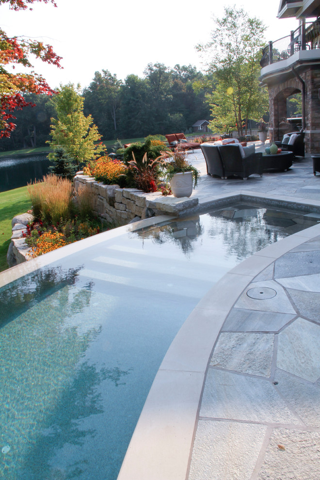 Foto de piscina infinita exótica grande a medida en patio trasero con suelo de baldosas