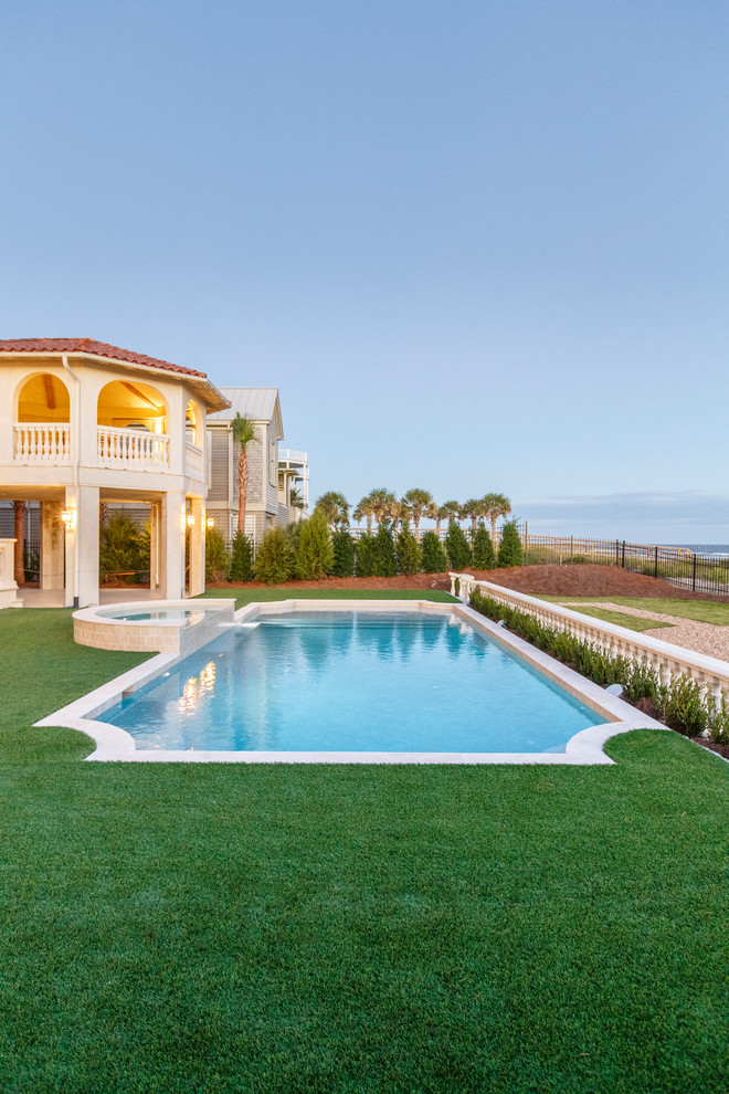 Ispirazione per una grande piscina mediterranea rettangolare dietro casa con una vasca idromassaggio e pavimentazioni in pietra naturale