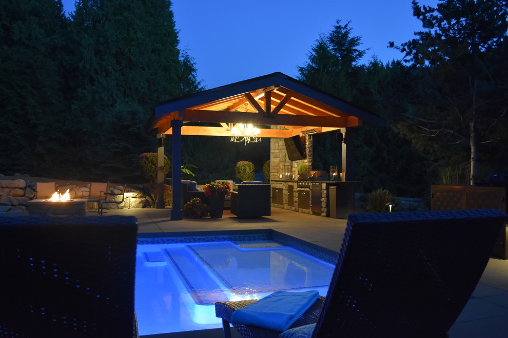 Foto di una grande piscina monocorsia american style rettangolare dietro casa con una vasca idromassaggio e lastre di cemento