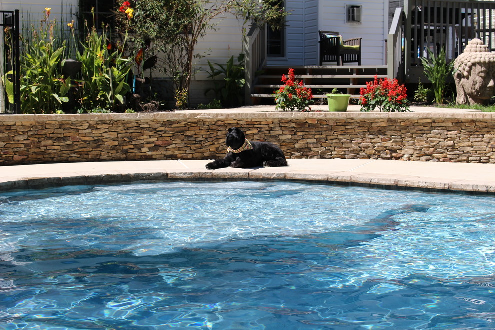 Modelo de piscina natural rústica de tamaño medio a medida en patio delantero con losas de hormigón